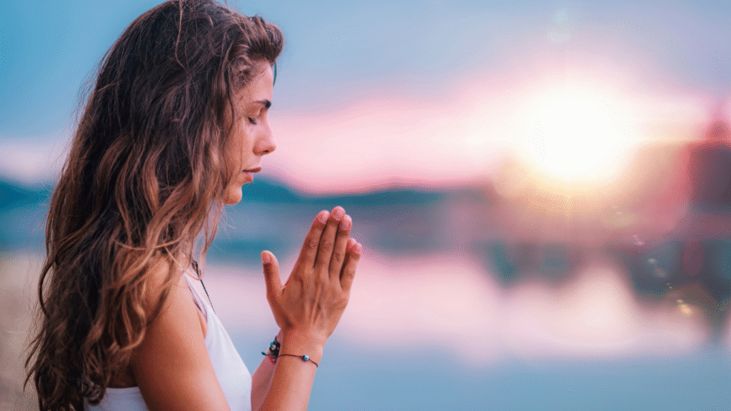Persona meditando frente a un lago al atardecer, representando paz interior y autoconocimiento en el viaje hacia una vida más consciente.