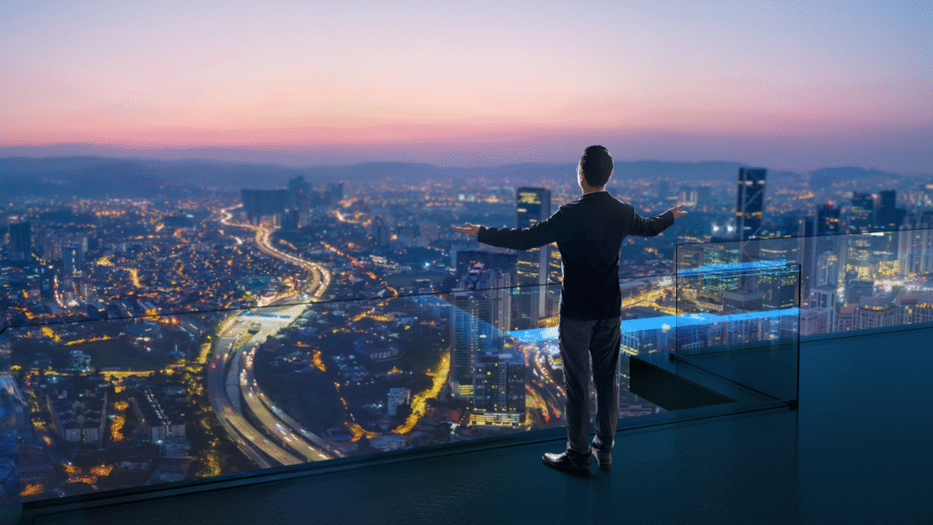 Hombre en la terraza de un edificio alto contemplando la ciudad con los brazos abiertos, simbolizando libertad y el cumplimiento de la misión de vivir una vida consciente.